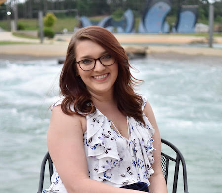 Julia sitting in a chair with the ocean behind her